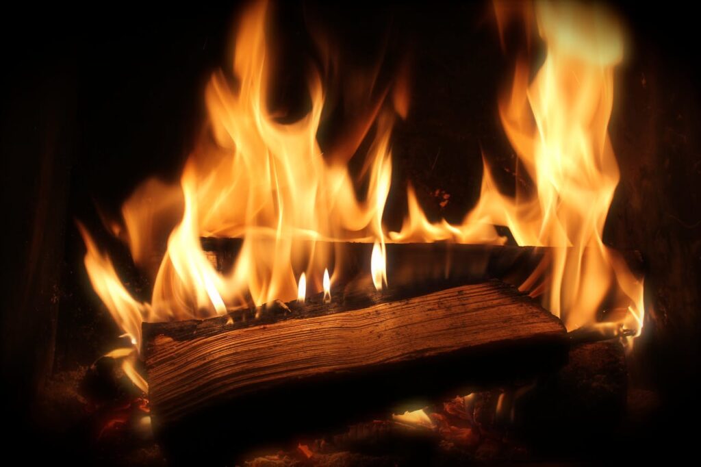 Close-up of a cozy fireplace with vibrant flames and firewood for warmth.