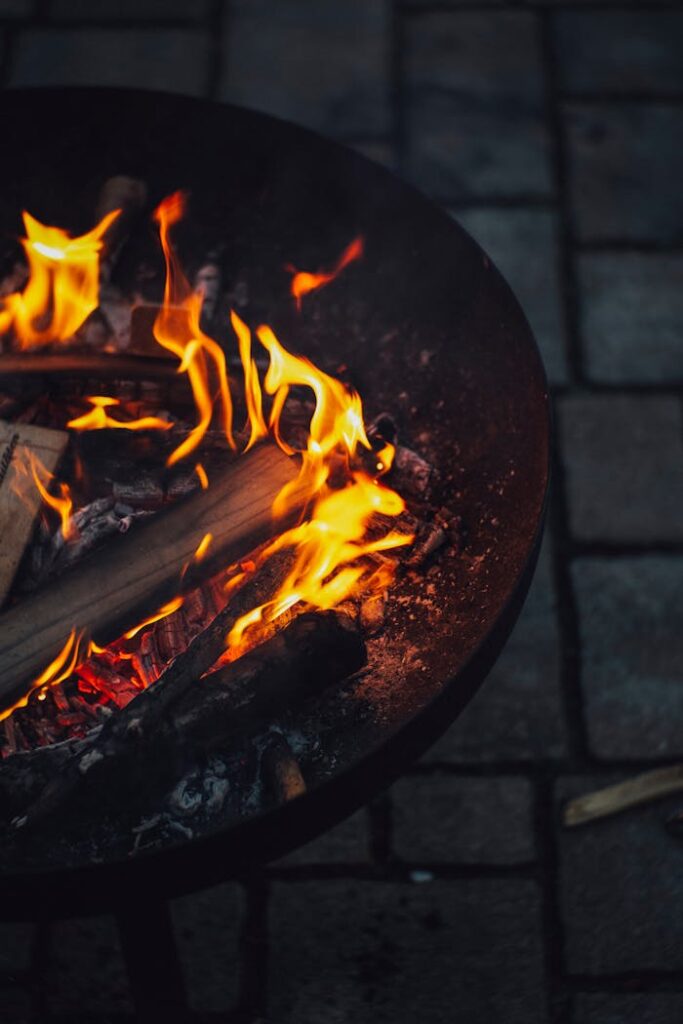 Warm and inviting fire pit at night with glowing flames and firewood.