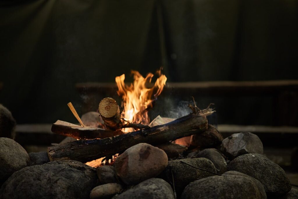 Warm campfire surrounded by rocks in an outdoor forest setting, ideal for camping evenings.